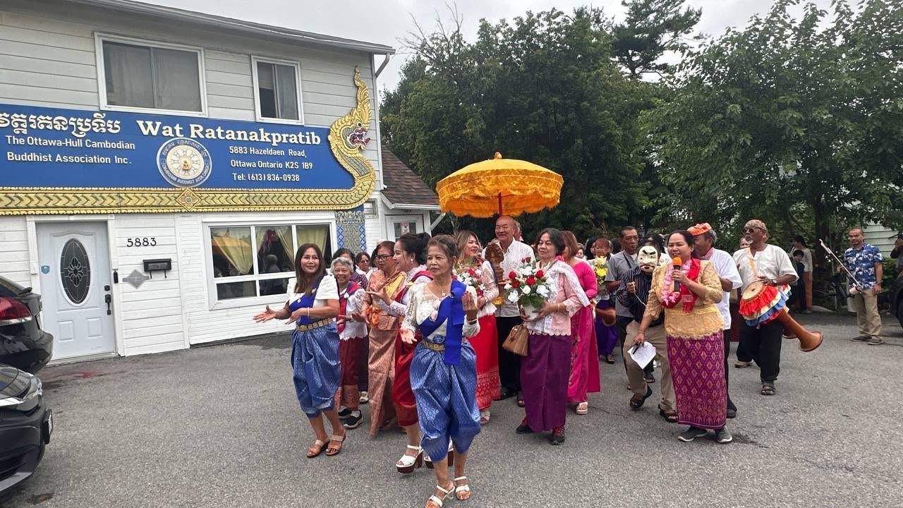 A procession in traditional Khmer dress in front of the temple sign