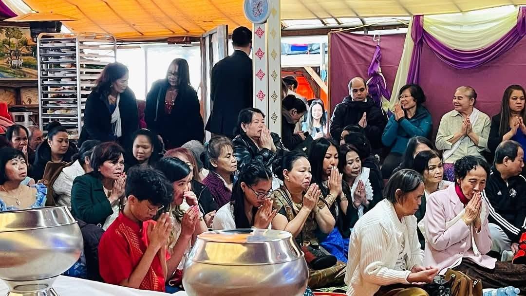 Families praying together beside a monk’s alms bowl in the festival hall